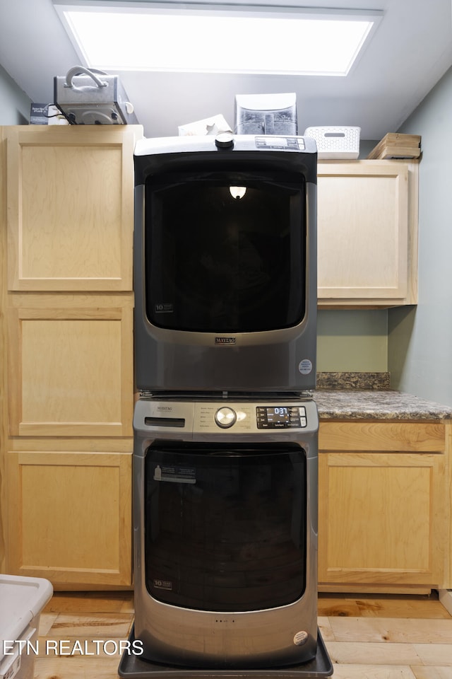 washroom featuring stacked washer and dryer and cabinets