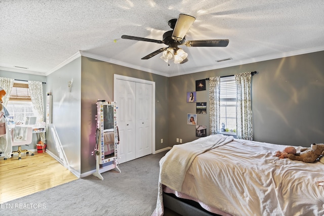 carpeted bedroom featuring ceiling fan, ornamental molding, a textured ceiling, and a closet