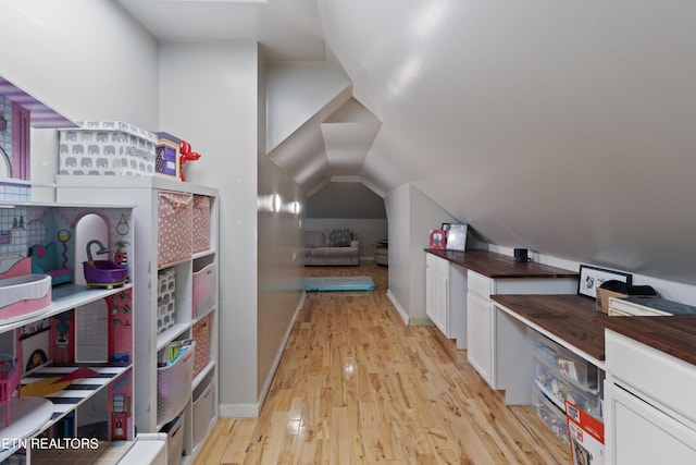 interior space with white cabinetry, light hardwood / wood-style flooring, and vaulted ceiling