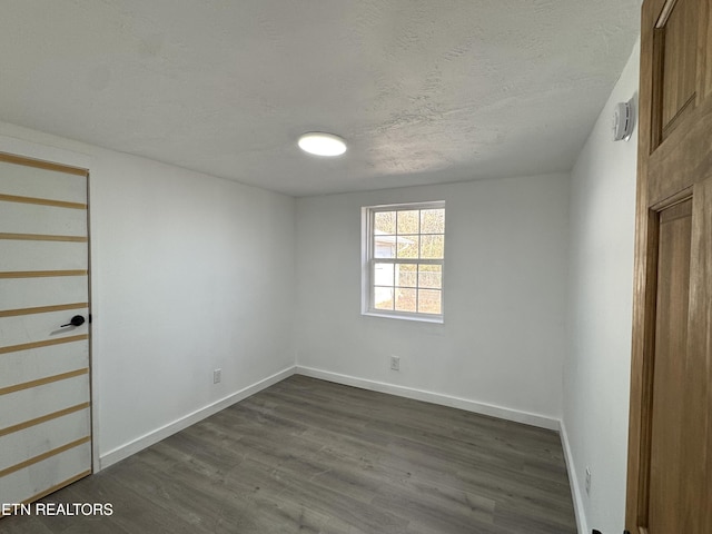 unfurnished room with a textured ceiling and dark hardwood / wood-style flooring