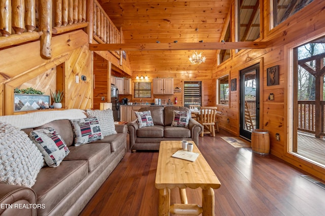 living room featuring dark hardwood / wood-style floors, a chandelier, high vaulted ceiling, and wood walls