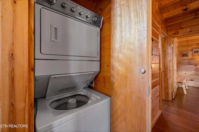 washroom with stacked washer / drying machine and wood walls