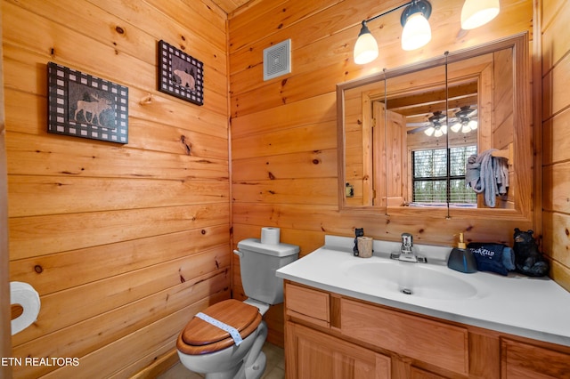 bathroom with vanity, wooden walls, and toilet