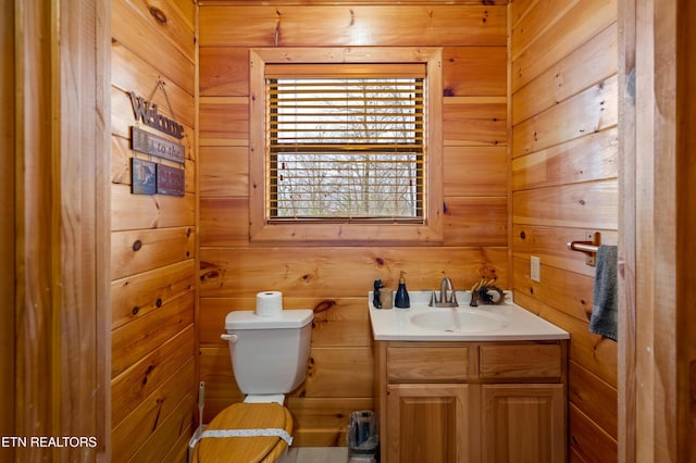 bathroom featuring wooden walls, vanity, and toilet