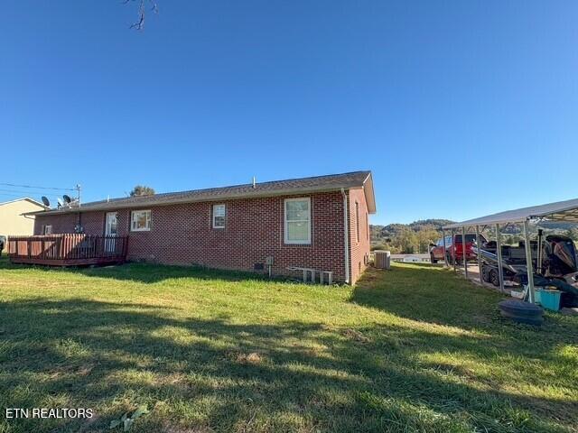 back of property with a wooden deck, a lawn, and central air condition unit