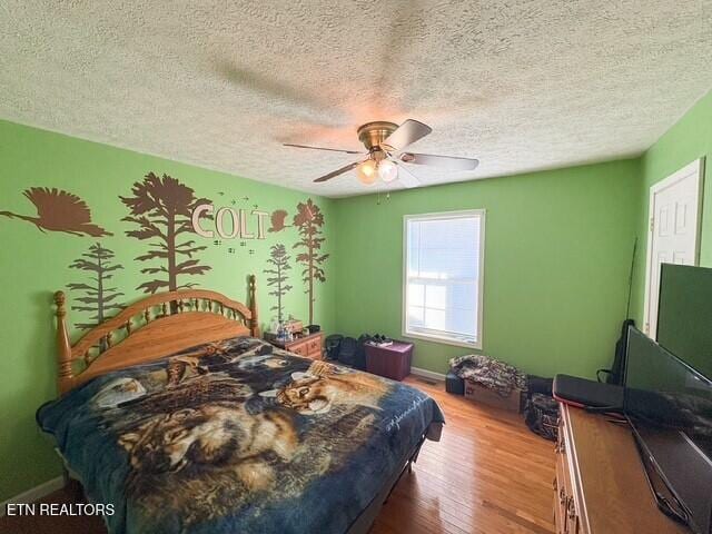 bedroom with ceiling fan, hardwood / wood-style floors, and a textured ceiling