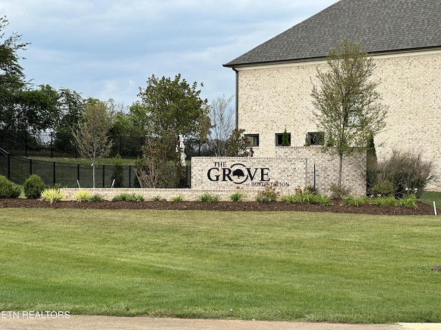 community / neighborhood sign with a yard and fence