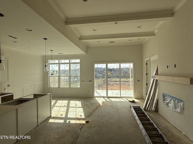 unfurnished living room featuring crown molding, wainscoting, and a decorative wall