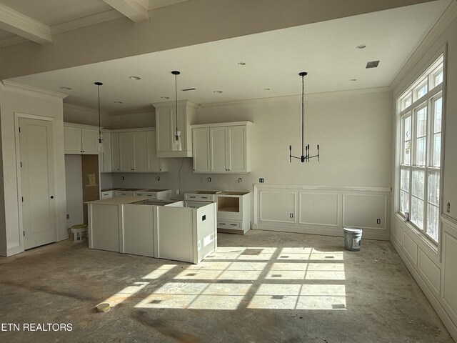 kitchen featuring ornamental molding, a kitchen island, white cabinetry, and a decorative wall