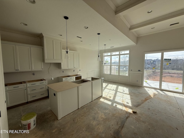 kitchen featuring ornamental molding, wainscoting, white cabinetry, and a decorative wall