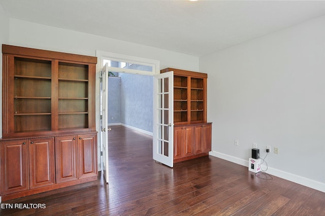 empty room with baseboards, dark wood finished floors, and french doors