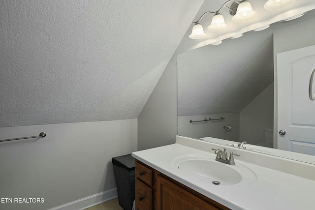 bathroom with lofted ceiling, baseboards, a textured ceiling, and vanity