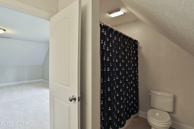 full bathroom featuring lofted ceiling, curtained shower, a textured ceiling, and baseboards