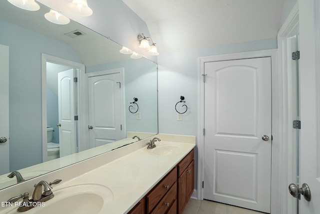 bathroom featuring double vanity, tile patterned flooring, a sink, and toilet