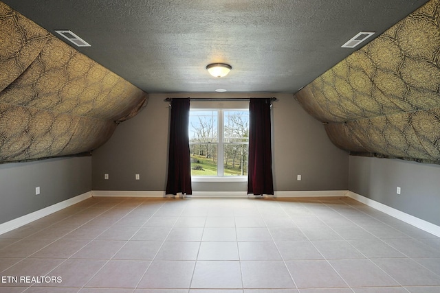 additional living space with light tile patterned floors, visible vents, and baseboards