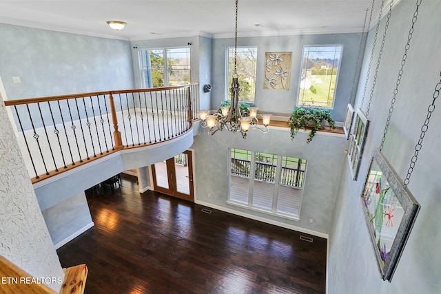 interior space with ornamental molding, wood finished floors, baseboards, and an inviting chandelier