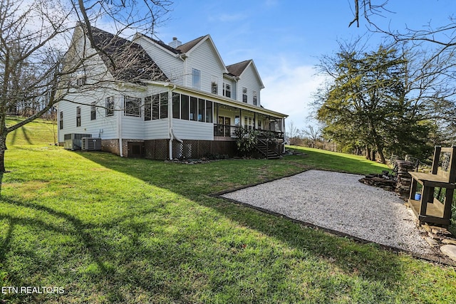 exterior space featuring a lawn, a sunroom, a chimney, stairway, and cooling unit