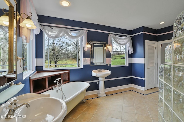full bathroom with a freestanding tub, tile patterned flooring, a wainscoted wall, a sink, and a closet