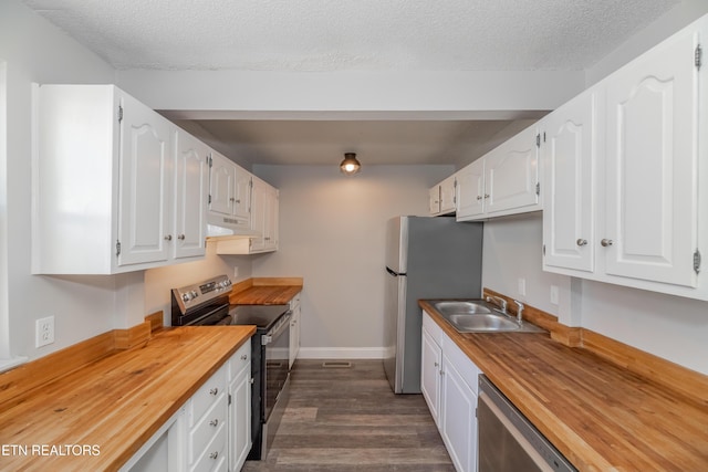 kitchen featuring wooden counters, stainless steel appliances, white cabinets, and sink