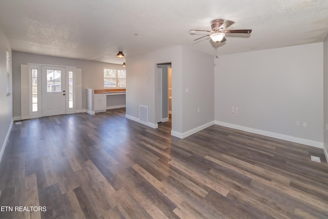 unfurnished living room featuring a textured ceiling, ceiling fan, and dark hardwood / wood-style floors