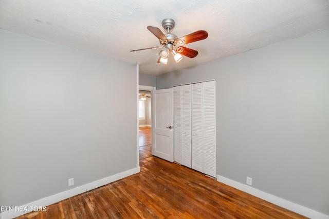 unfurnished bedroom with ceiling fan, dark wood-type flooring, and a closet