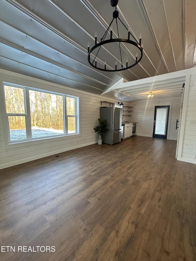 unfurnished living room with dark hardwood / wood-style flooring and an inviting chandelier