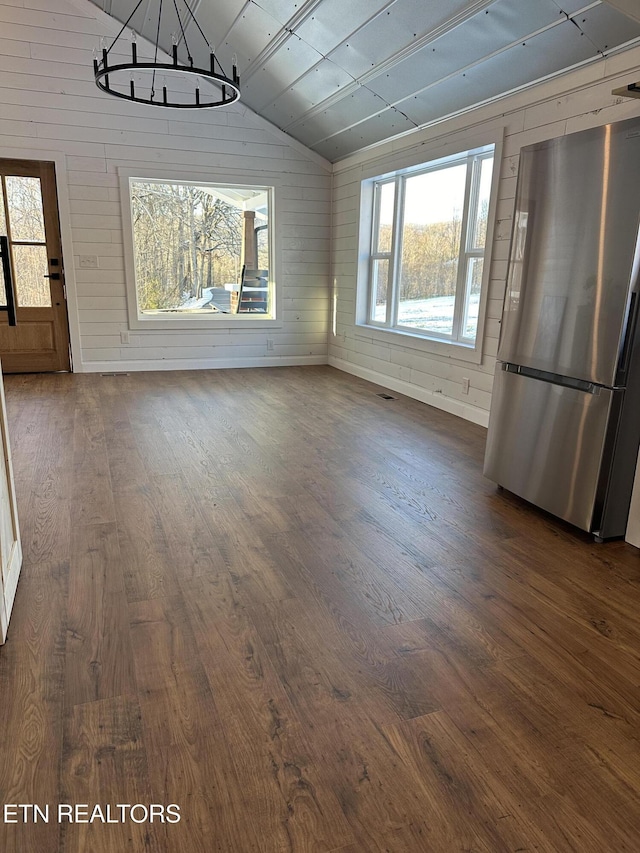 unfurnished dining area featuring dark hardwood / wood-style floors, lofted ceiling, and wood walls