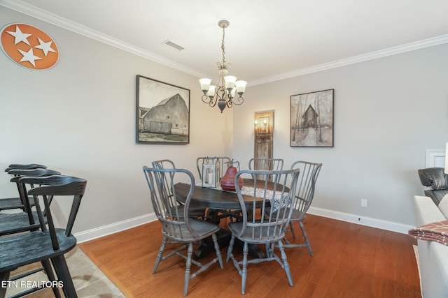 dining area with hardwood / wood-style floors, ornamental molding, and a chandelier