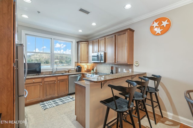 kitchen featuring kitchen peninsula, a kitchen breakfast bar, light stone countertops, stainless steel appliances, and sink