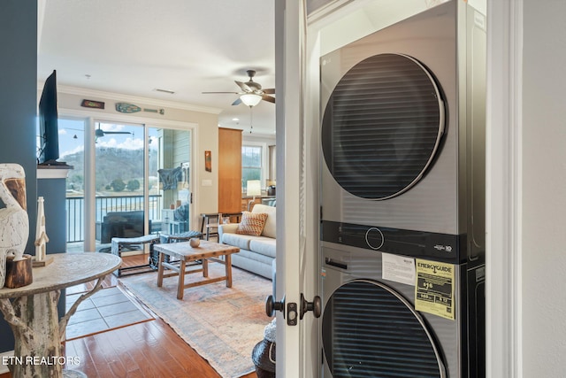 interior space with stacked washer / dryer, crown molding, ceiling fan, and hardwood / wood-style flooring