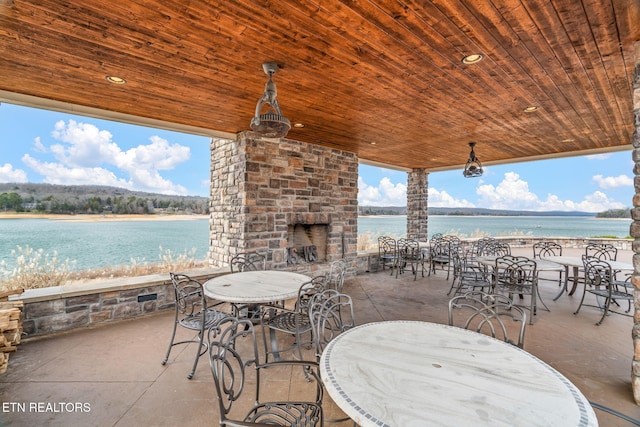 view of patio with an outdoor stone fireplace and a water view