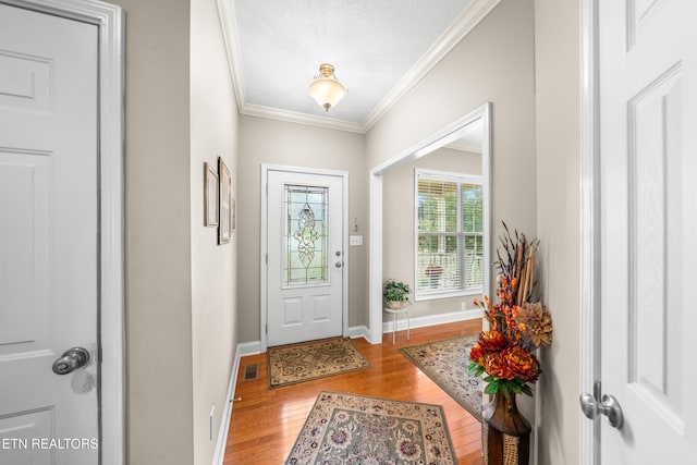 entryway with light hardwood / wood-style flooring, a textured ceiling, and ornamental molding