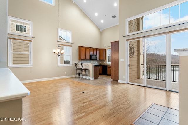 living room featuring a notable chandelier, a towering ceiling, crown molding, and light hardwood / wood-style flooring