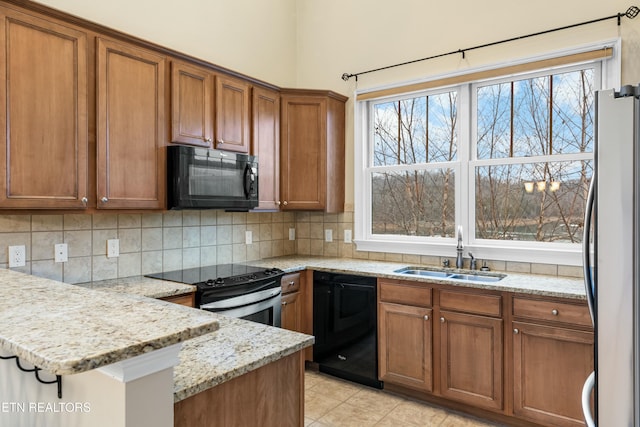 kitchen featuring backsplash, light stone countertops, sink, and black appliances