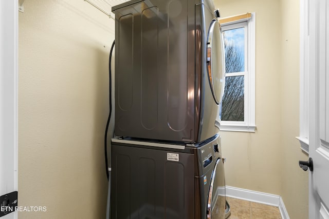 laundry room with light tile patterned floors, stacked washer / drying machine, and a healthy amount of sunlight