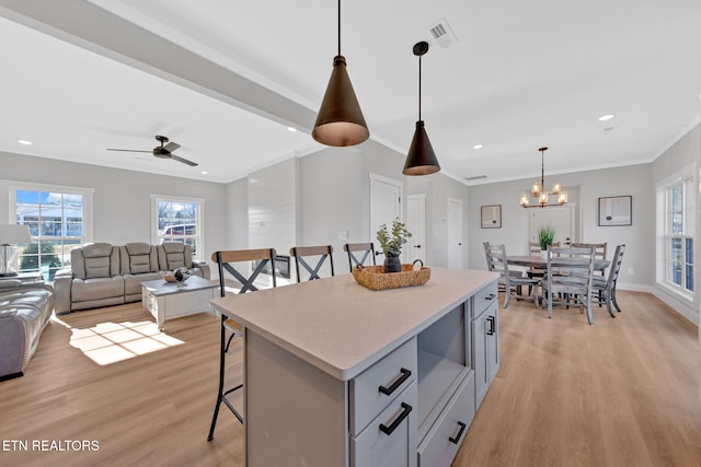 kitchen with a breakfast bar area, a center island, hanging light fixtures, light hardwood / wood-style flooring, and gray cabinets