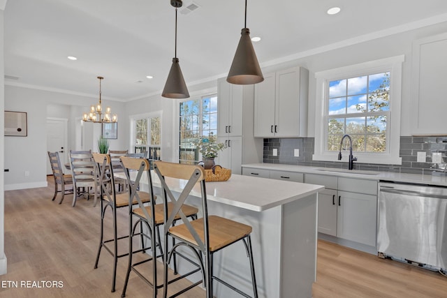 kitchen with pendant lighting, sink, dishwasher, white cabinetry, and a kitchen island