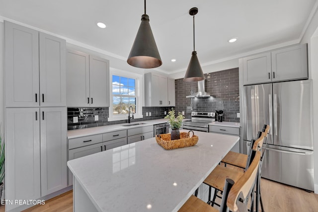 kitchen with tasteful backsplash, hanging light fixtures, a kitchen island, stainless steel appliances, and light stone countertops