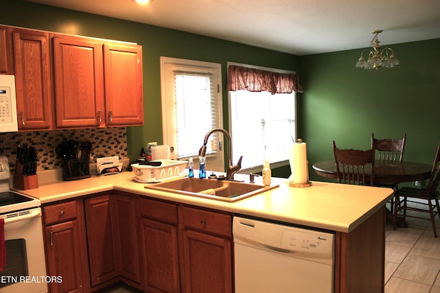 kitchen with sink, an inviting chandelier, tasteful backsplash, kitchen peninsula, and white appliances