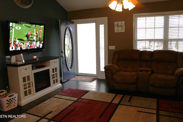 living room featuring vaulted ceiling, ceiling fan, and dark wood-type flooring