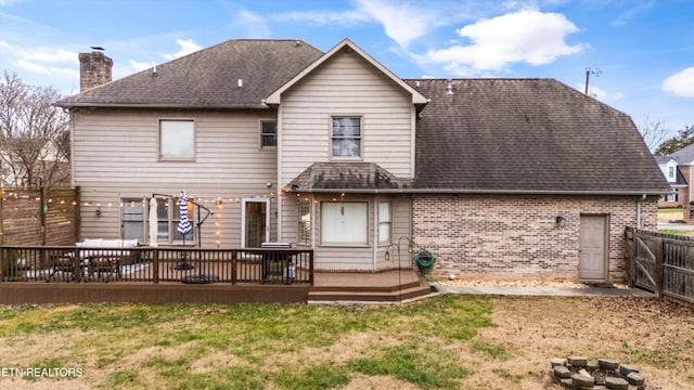 back of house featuring a lawn and a wooden deck