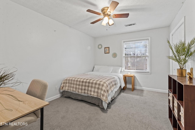 bedroom with ceiling fan, light carpet, and a textured ceiling