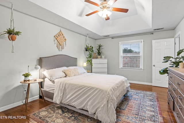 bedroom with a tray ceiling, ceiling fan, and dark hardwood / wood-style floors