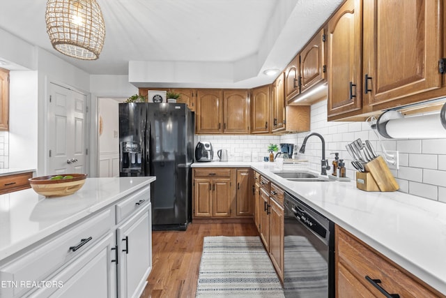 kitchen with black appliances, white cabinets, sink, light hardwood / wood-style flooring, and tasteful backsplash