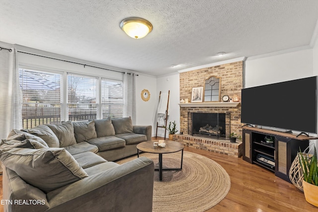 living room with hardwood / wood-style floors, crown molding, a textured ceiling, and a brick fireplace