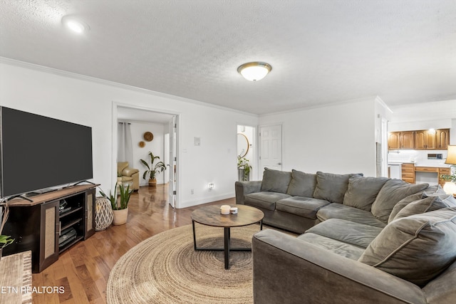 living room featuring light hardwood / wood-style flooring, a textured ceiling, and ornamental molding