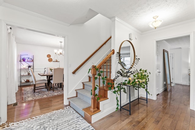 foyer featuring hardwood / wood-style floors, a textured ceiling, an inviting chandelier, and ornamental molding