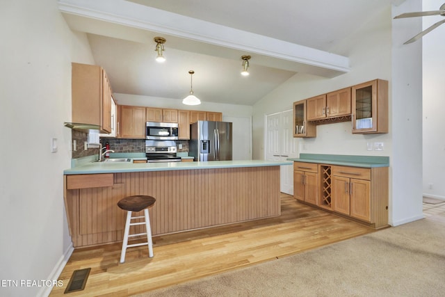 kitchen with sink, stainless steel appliances, vaulted ceiling with beams, kitchen peninsula, and pendant lighting