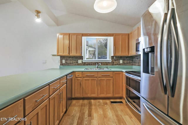 kitchen featuring sink, stainless steel appliances, backsplash, light hardwood / wood-style floors, and vaulted ceiling