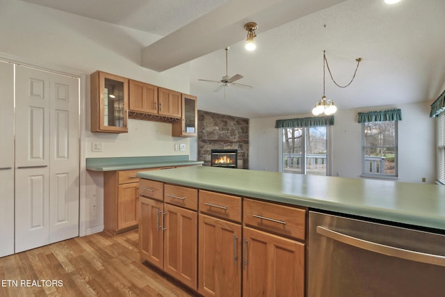 kitchen featuring dishwasher, a stone fireplace, lofted ceiling, ceiling fan with notable chandelier, and light wood-type flooring